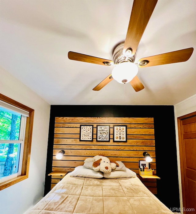 bedroom with ceiling fan and wooden walls