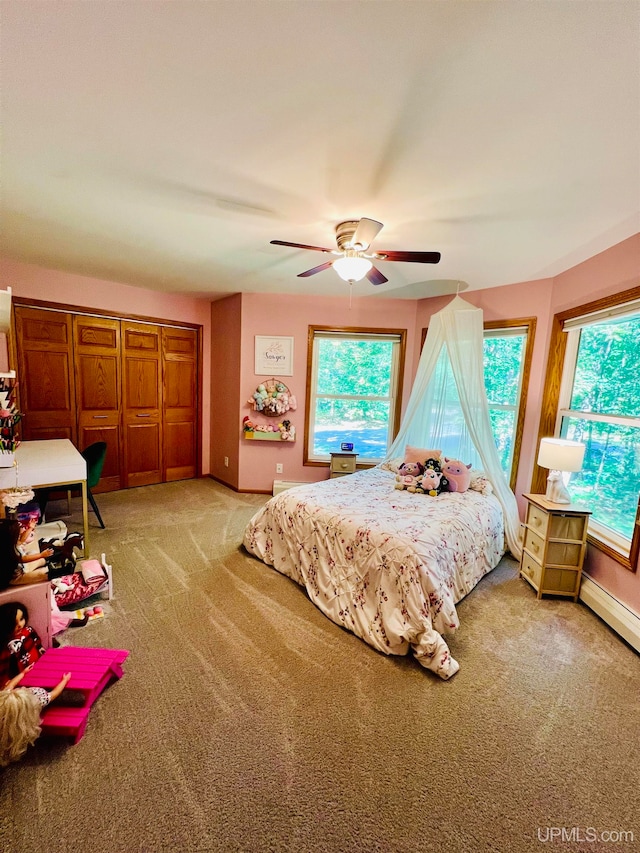 carpeted bedroom featuring a baseboard heating unit and ceiling fan