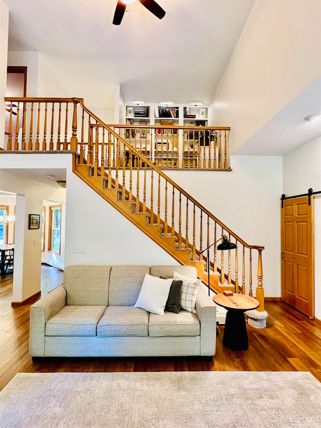 living room featuring a barn door, ceiling fan, and wood-type flooring