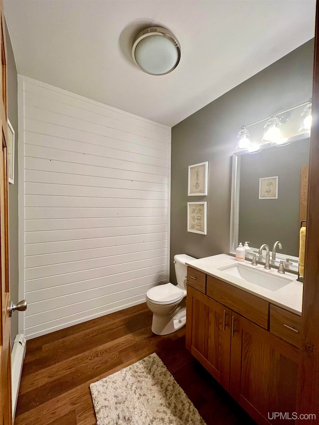 bathroom with wood-type flooring, toilet, a baseboard radiator, and vanity