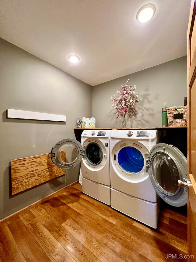 clothes washing area with separate washer and dryer and wood-type flooring