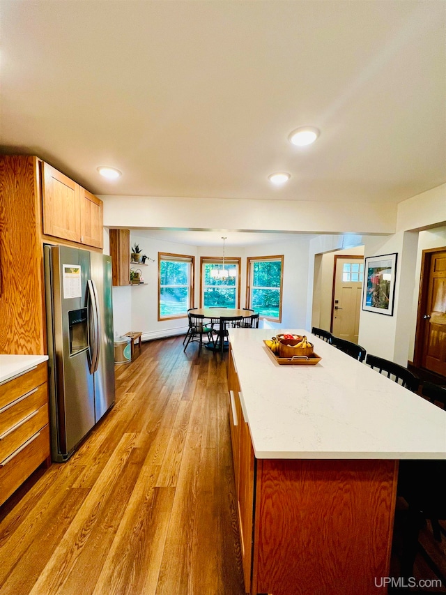 kitchen featuring hardwood / wood-style floors, stainless steel fridge, a kitchen island, and pendant lighting