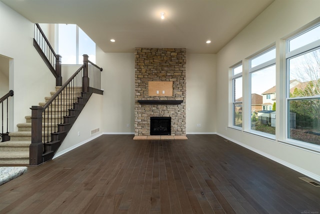 unfurnished living room featuring dark hardwood / wood-style flooring and a stone fireplace