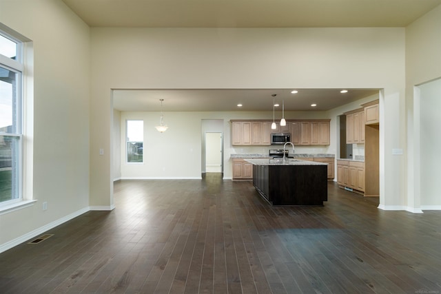 kitchen featuring dark wood-type flooring, pendant lighting, sink, and a kitchen island with sink