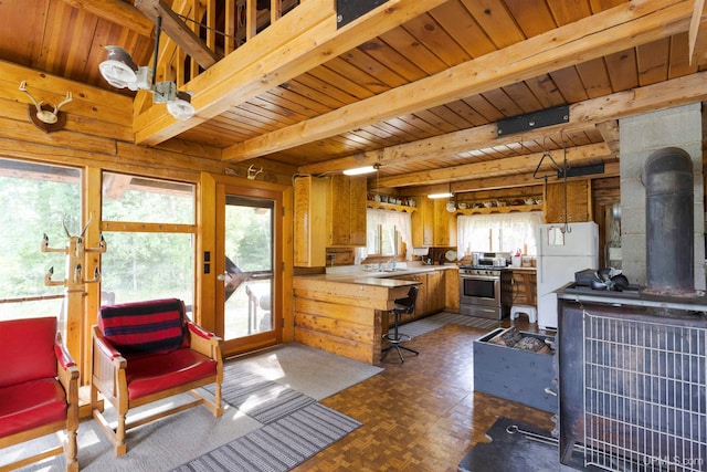 kitchen with gas range, a wood stove, white fridge, parquet floors, and beam ceiling