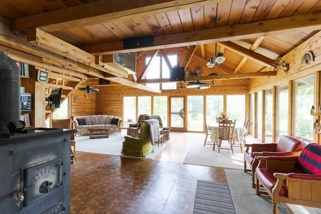 living room with a fireplace, beamed ceiling, a wealth of natural light, and a wood stove