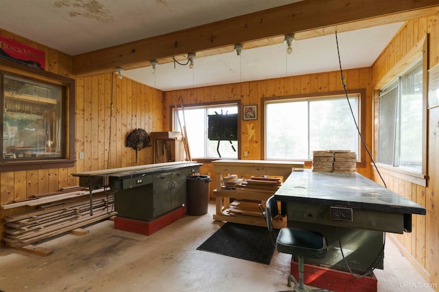 miscellaneous room with wood walls, beamed ceiling, and concrete flooring