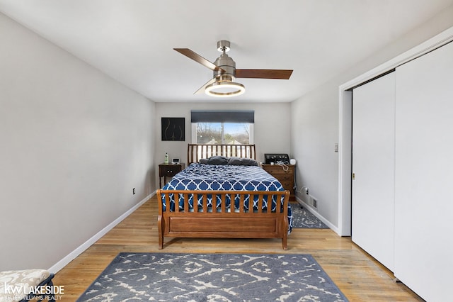 bedroom with ceiling fan, wood finished floors, visible vents, and baseboards