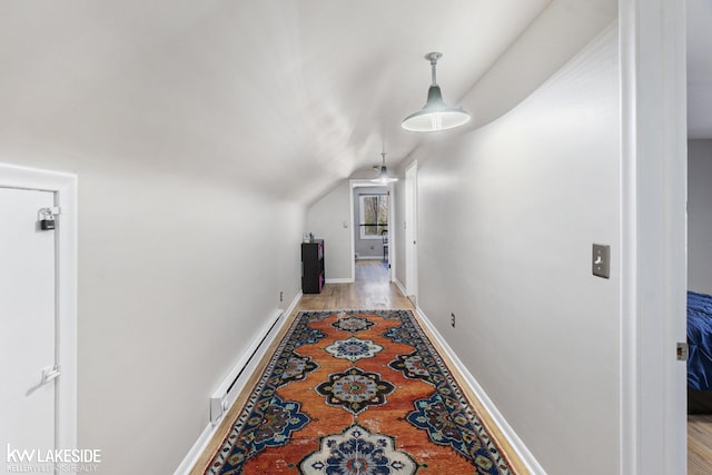 hall featuring a baseboard heating unit, vaulted ceiling, and baseboards