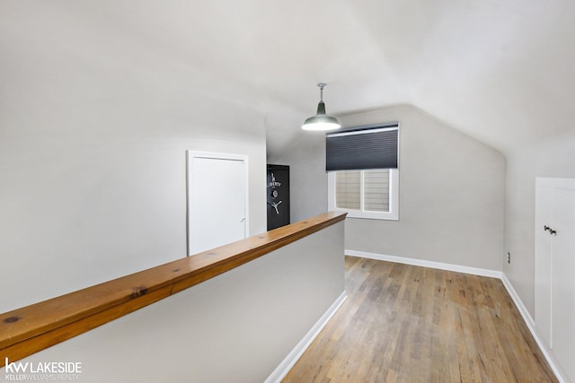 corridor featuring an upstairs landing, vaulted ceiling, baseboards, and wood finished floors