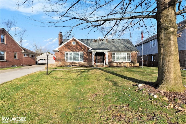 view of front facade featuring driveway, a chimney, a front lawn, and brick siding