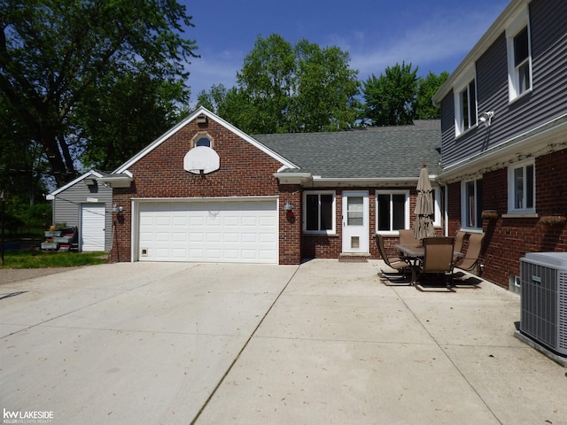 view of front of property with driveway, a garage, central AC unit, roof with shingles, and brick siding