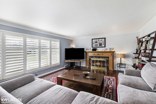 living area with a fireplace, crown molding, baseboards, and wood finished floors