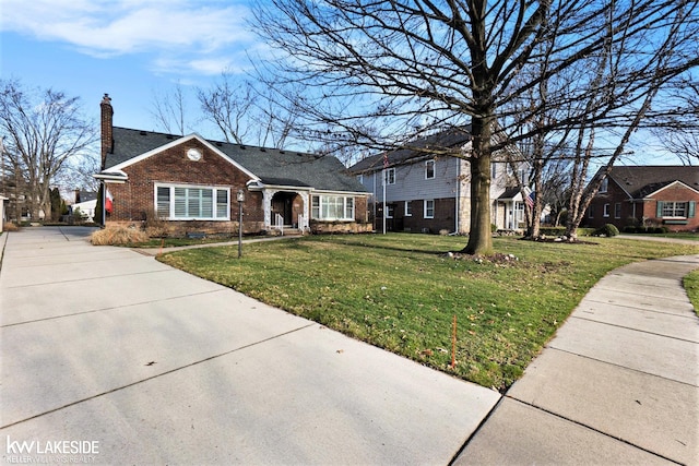 view of front of home with brick siding, a chimney, and a front yard