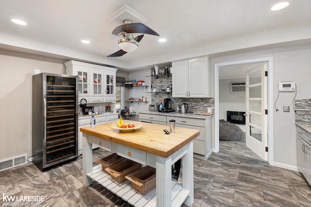 kitchen with beverage cooler, wood counters, and white cabinets