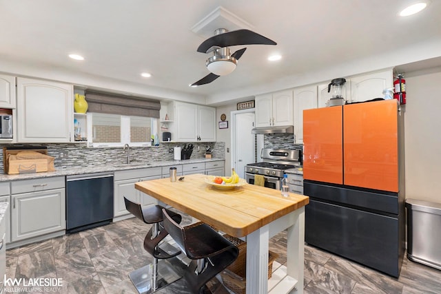 kitchen with white cabinets, appliances with stainless steel finishes, light stone counters, sink, and tasteful backsplash