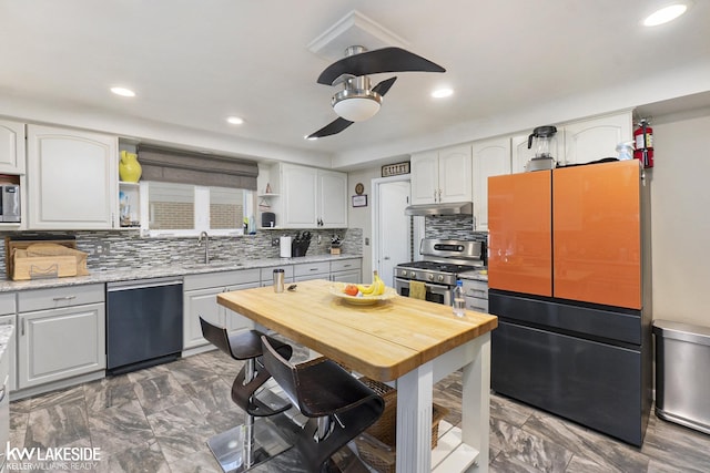 kitchen with open shelves, freestanding refrigerator, stainless steel gas range, under cabinet range hood, and dishwashing machine