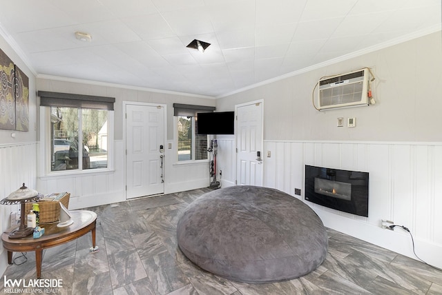 living area featuring a wealth of natural light, an AC wall unit, a glass covered fireplace, and crown molding