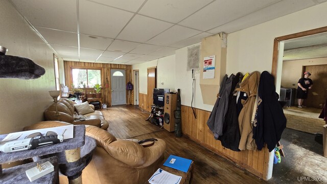 living room featuring wood walls, hardwood / wood-style flooring, and a drop ceiling