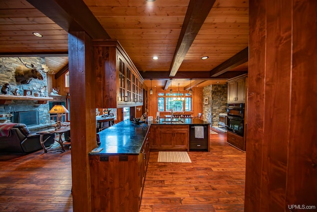 kitchen featuring dark wood-type flooring, a fireplace, beam ceiling, and kitchen peninsula