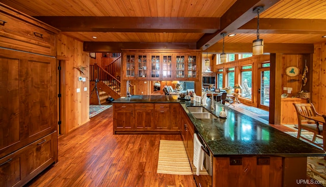 kitchen featuring wooden walls, decorative light fixtures, sink, dark wood-type flooring, and beam ceiling