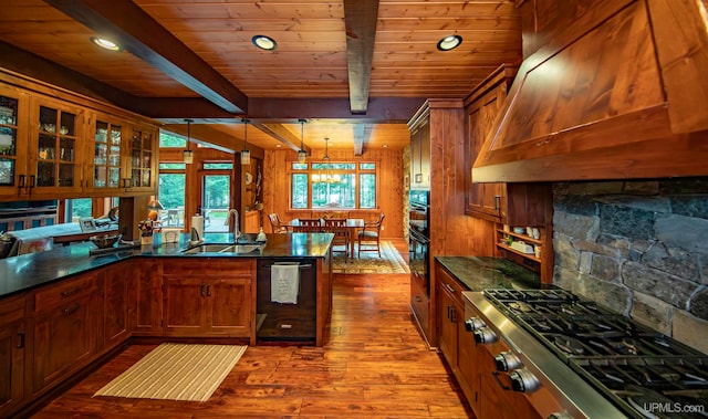 kitchen featuring hardwood / wood-style floors, custom exhaust hood, sink, hanging light fixtures, and appliances with stainless steel finishes