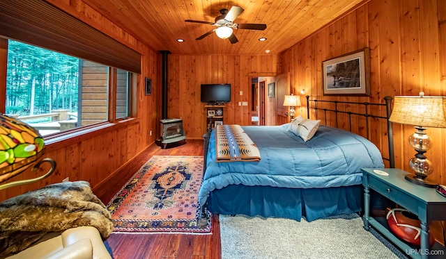 bedroom featuring ceiling fan, wood walls, and wood-type flooring