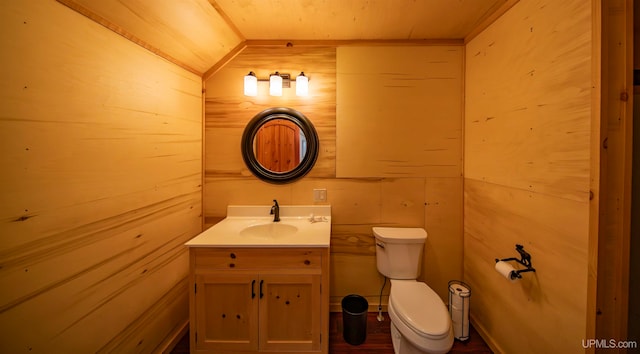 bathroom with wood walls, toilet, and vanity