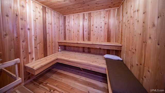 view of sauna / steam room featuring wood ceiling, wood-type flooring, and wooden walls