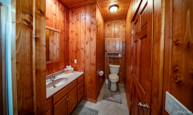 bathroom featuring vanity, wood walls, wood ceiling, tile patterned flooring, and toilet