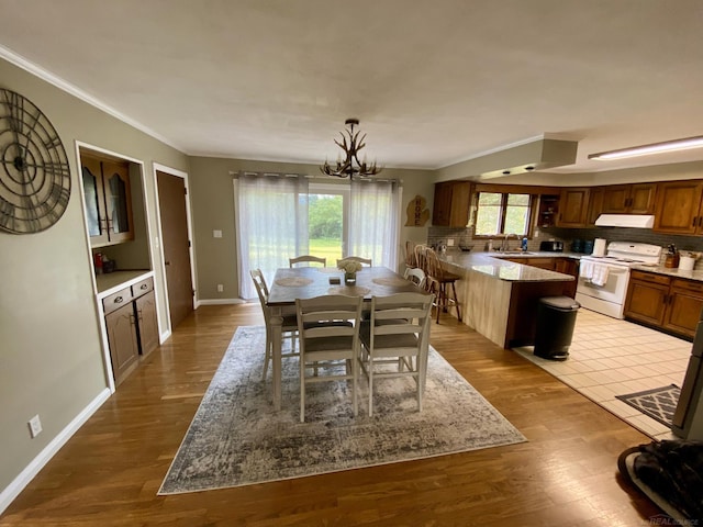 dining room featuring ornamental molding, light hardwood / wood-style flooring, sink, and a notable chandelier