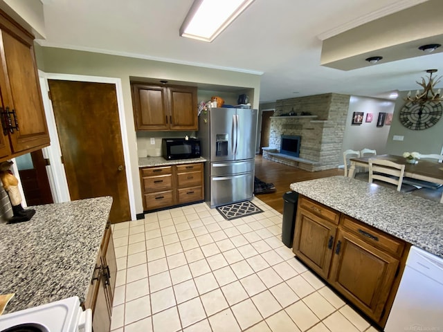 kitchen with a fireplace, white appliances, light stone counters, and light tile patterned floors