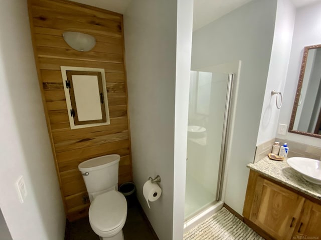 bathroom with vanity, toilet, wooden walls, and a shower with door