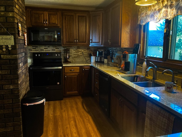 kitchen featuring hardwood / wood-style floors, a textured ceiling, black appliances, sink, and light stone countertops