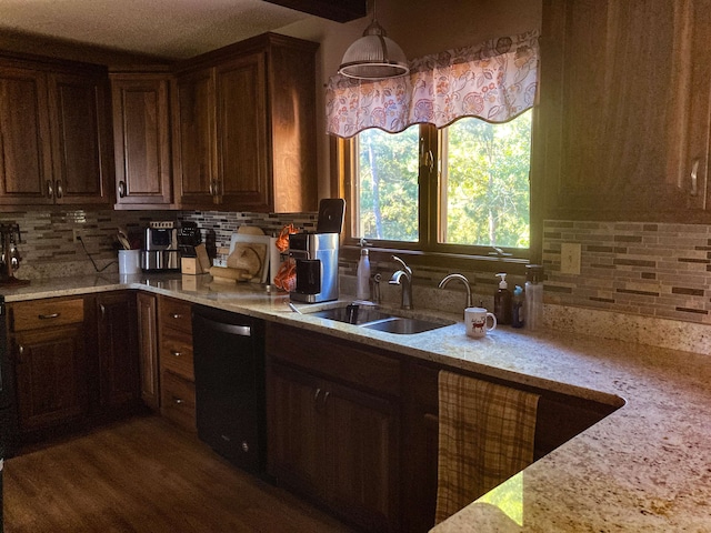 kitchen featuring hanging light fixtures, light stone countertops, dark hardwood / wood-style flooring, sink, and black dishwasher