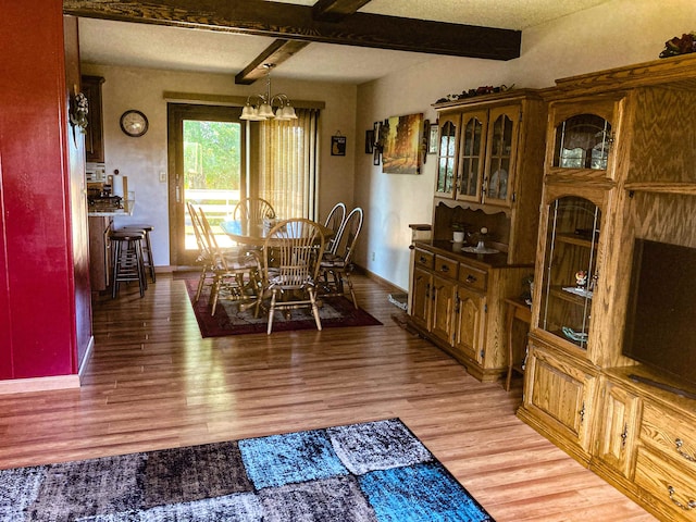 dining room featuring beamed ceiling, hardwood / wood-style floors, an inviting chandelier, and a textured ceiling