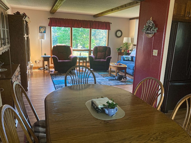 dining room featuring hardwood / wood-style floors, beamed ceiling, and a textured ceiling