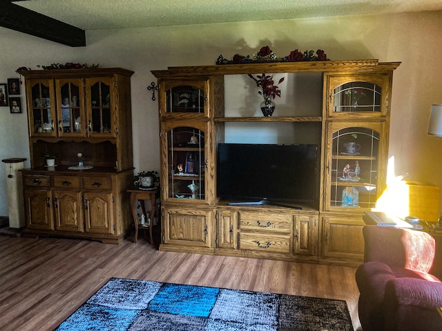 living room featuring a textured ceiling, beamed ceiling, and wood-type flooring