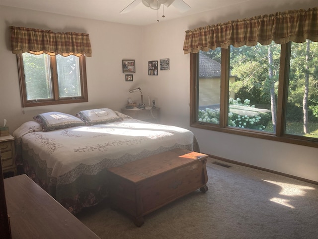 bedroom with dark carpet, ceiling fan, and multiple windows