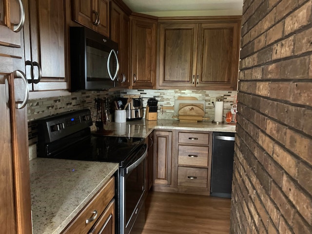 kitchen featuring dark hardwood / wood-style flooring, brick wall, stainless steel appliances, and light stone countertops