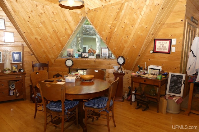 dining space featuring wood finished floors, lofted ceiling, wood walls, and wooden ceiling