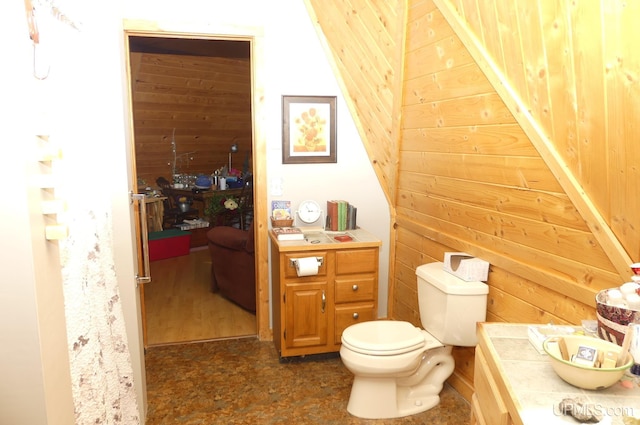 bathroom featuring toilet and wood walls