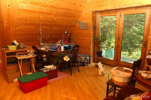 office with vaulted ceiling, plenty of natural light, wooden walls, and wood finished floors