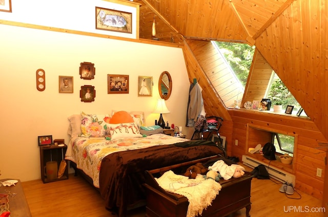 bedroom with a baseboard heating unit, lofted ceiling, and wood finished floors