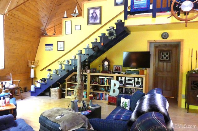 living area featuring stairway, wood finished floors, wooden walls, and a towering ceiling