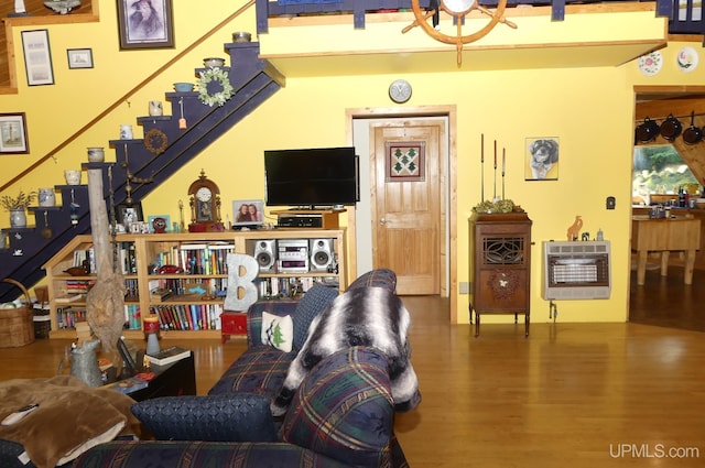 living room with heating unit, stairs, and wood finished floors