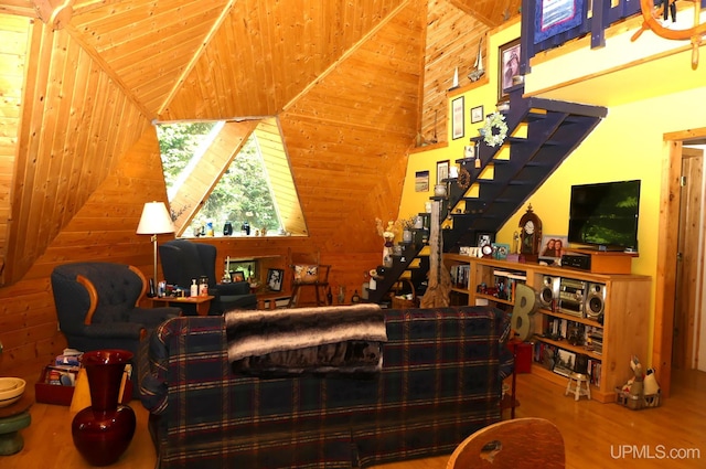 interior space with stairway, wood walls, lofted ceiling, and wood finished floors