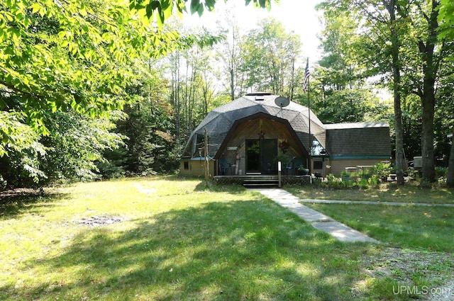 exterior space featuring a gambrel roof, a shingled roof, and a front yard