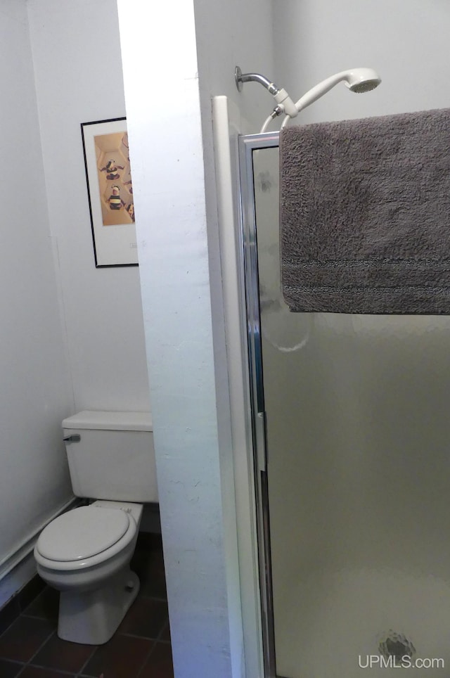 bathroom with tile patterned floors, toilet, and a shower stall