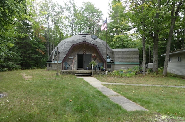 view of front facade with a deck, a shingled roof, and a front lawn